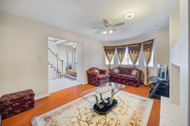 Living area featuring wood finished floors, ceiling fan, and stairs | Image 4