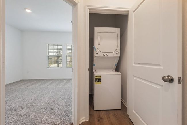 Laundry room featuring stacked washing machine and dryer and baseboards | Image 12