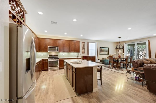 Kitchen featuring a sink, a breakfast bar, light wood-type flooring, stainless steel appliances, and visible vents | Image 16