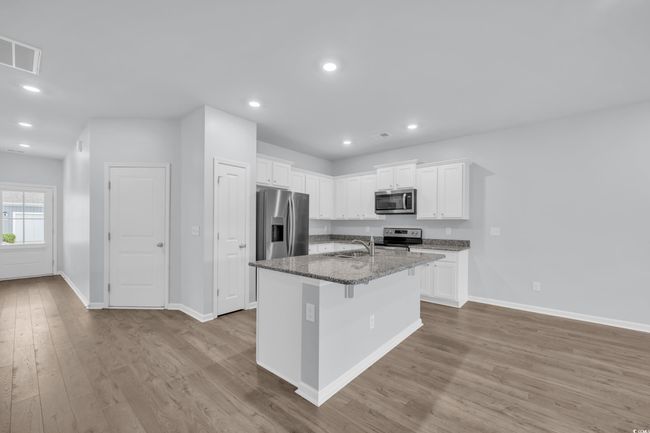 Kitchen with visible vents, a sink, wood finished floors, white cabinetry, and stainless steel appliances | Image 4
