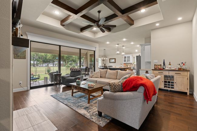 Living area with coffered ceiling, dark wood finished floors, ceiling fan, recessed lighting, and beam ceiling | Image 4
