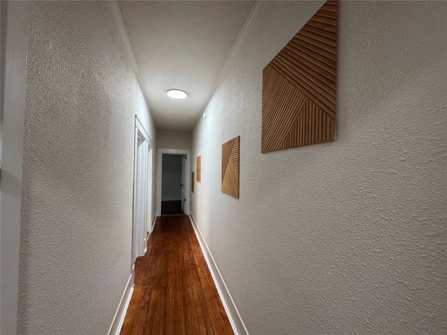 Corridor with baseboards, wood finished floors, ornamental molding, and a textured wall | Image 5