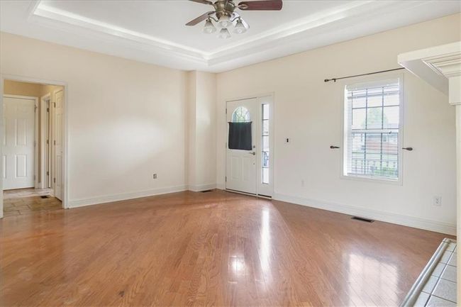 Foyer entrance featuring baseboards, ceiling fan, light wood-style flooring, and a tray ceiling | Image 10