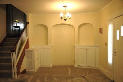 Entryway featuring crown molding, a notable chandelier, and dark colored carpet | Image 3