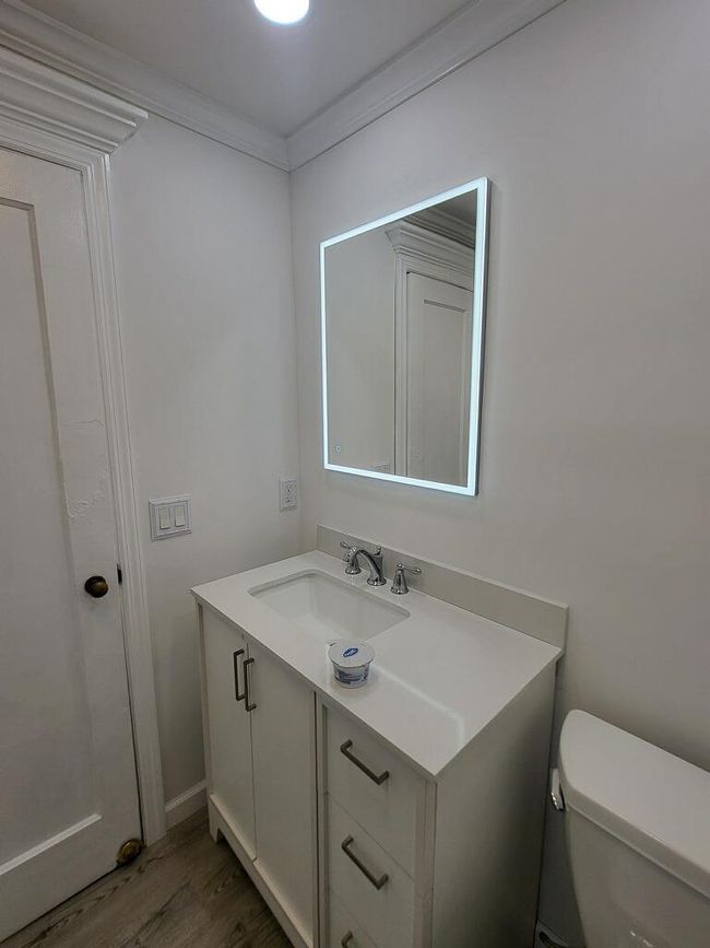 Bathroom with wood finished floors, toilet, vanity, and crown molding | Image 35