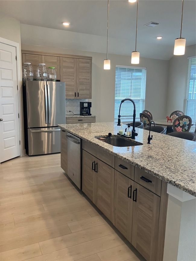 Kitchen featuring refrigerator, dishwasher, a sink, light wood finished floors, and pendant lighting | Image 9