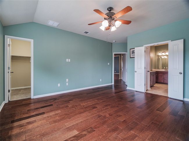 Unfurnished bedroom featuring a walk in closet, wood finished floors, a chandelier, baseboards, and ensuite bathroom | Image 24
