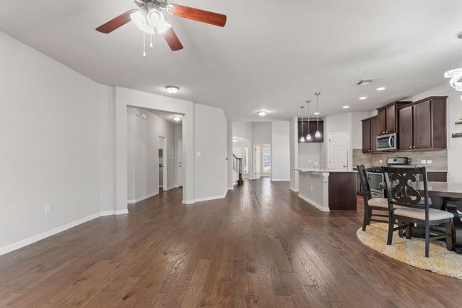Living room with dark wood-type flooring, baseboards, arched walkways, visible vents, and a ceiling fan | Image 15