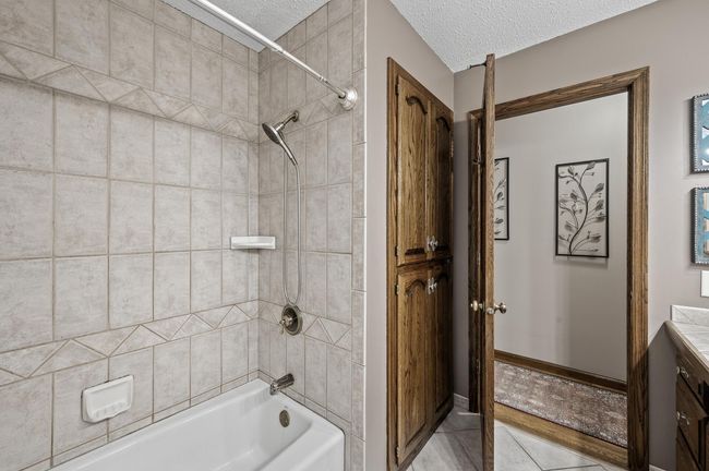 Tub to ceiling tile and extra in bathroom storage behind the solid wood door | Image 35