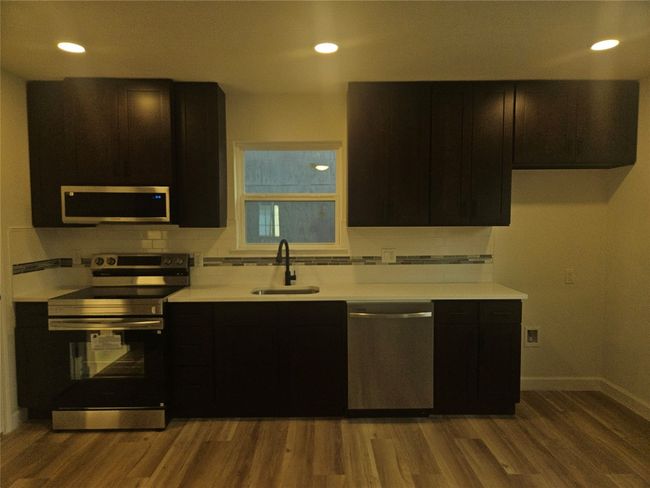 Kitchen with tasteful backsplash, wood finished floors, stainless steel appliances, and a sink | Image 5