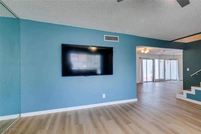 Unfurnished living room with wood finished floors, stairway, and a textured ceiling | Image 11