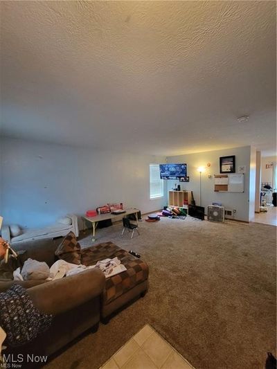 Unfurnished living room with a textured ceiling and light carpet | Image 3