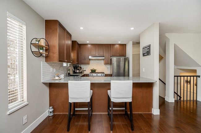 Kitchen with a sink, freestanding refrigerator, a peninsula, and under cabinet range hood | Image 4