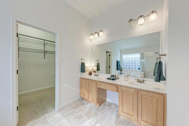 Full bath featuring a sink, a spacious closet, double vanity, tile patterned flooring, and a stall shower | Image 24