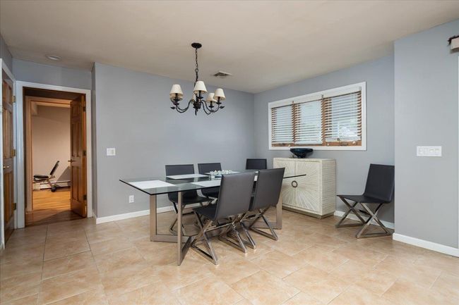 Dining space featuring a chandelier, light tile patterned flooring, and a baseboard heating unit | Image 8