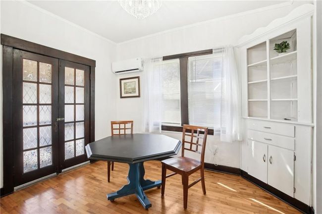 Dining room with a wall mounted air conditioner, french doors, light wood-type flooring, crown molding, and a notable chandelier | Image 8