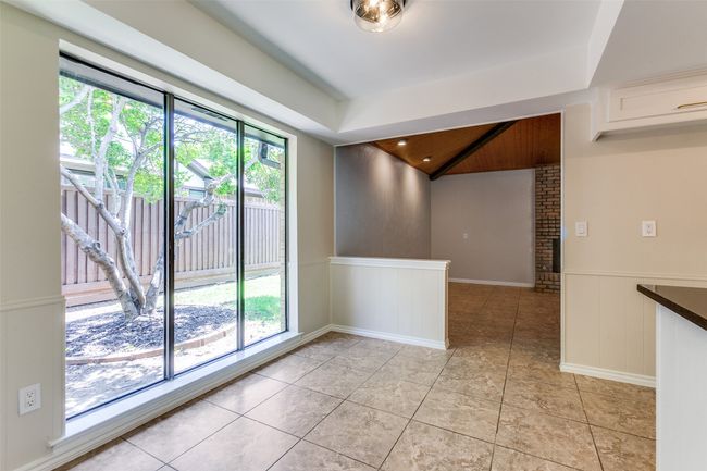 Spare room featuring a wainscoted wall, light tile patterned floors, a decorative wall, and lofted ceiling | Image 17