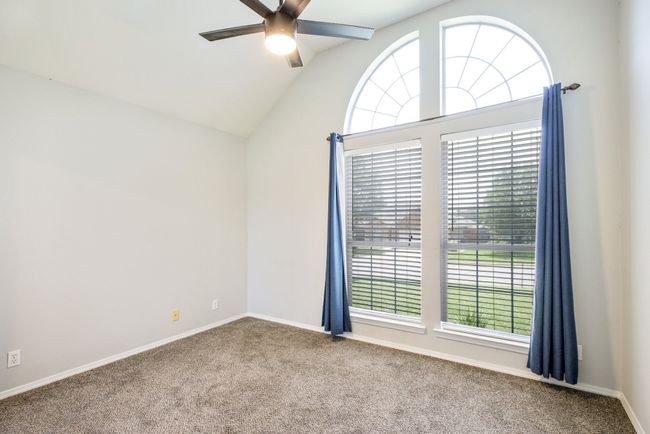 Carpeted empty room with ceiling fan, healthy amount of natural light, and lofted ceiling | Image 12