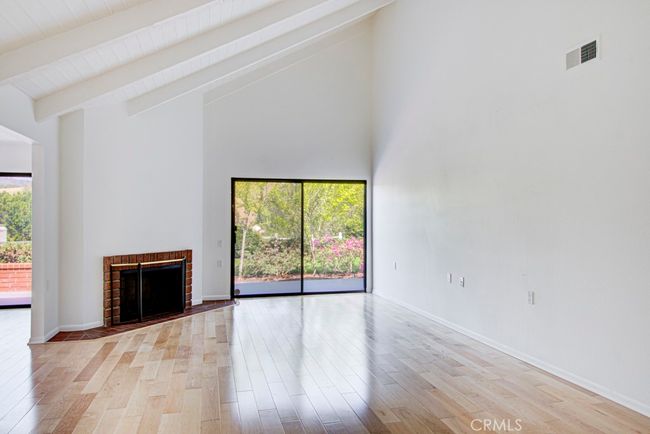 Large living room has a vaulted ceiling, wood-burning fireplace and a glass slider that opens to the rear patio. | Image 6