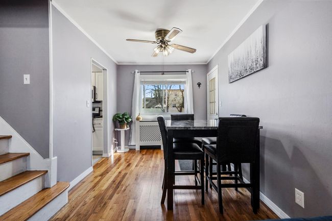 Dining space with crown molding, baseboards, stairway, ceiling fan, and hardwood / wood-style flooring | Image 5