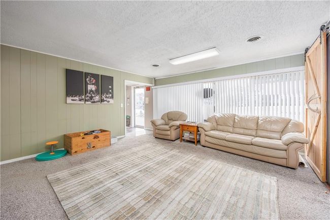 Living room with visible vents, a barn door, and a textured ceiling | Image 7