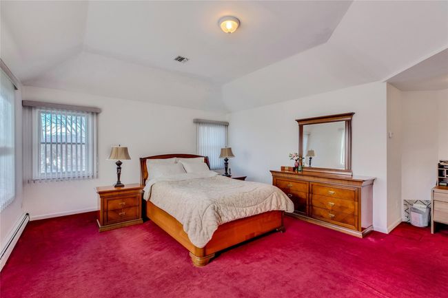 Bedroom featuring carpet floors, vaulted ceiling, and a baseboard radiator | Image 13