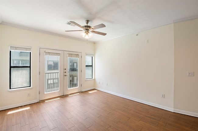 Empty room featuring french doors, ornamental molding, light wood finished floors, and a ceiling fan | Image 12