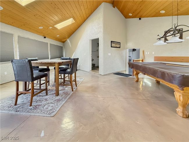 Game room featuring high vaulted ceiling, wooden ceiling, pool table, concrete flooring, and a textured wall | Image 36