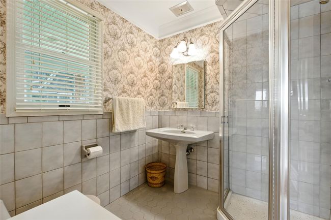 Full bath with crown molding, a stall shower, wallpapered walls, tile patterned flooring, and tile walls | Image 25