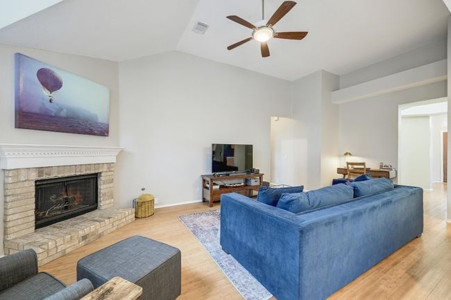 Family Room area with a ceiling fan, wood finished floors, vaulted ceiling, and a brick fireplace | Image 20