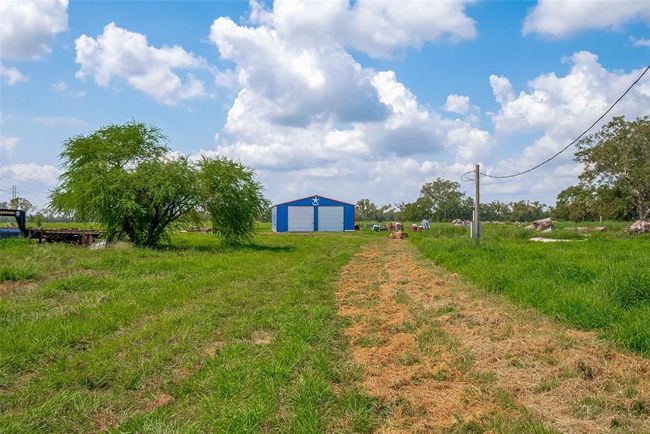 Set against lush surroundings, the bright blue barn/shop stands out as both functional and eye-catching. Massive open spaces around it amplify its utility. | Image 36