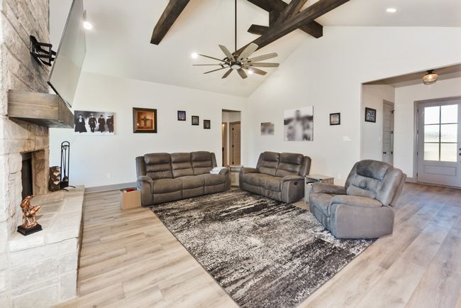 Living area with wood finished floors, beamed ceiling, baseboards, high vaulted ceiling, and a ceiling fan | Image 17
