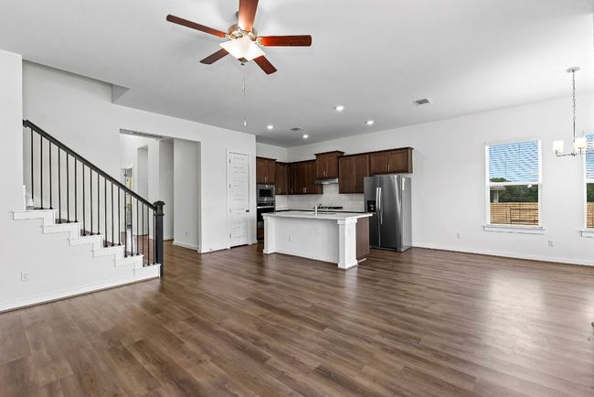 Unfurnished living room with a ceiling fan, dark wood finished floors, a chandelier, baseboards, and recessed lighting | Image 19