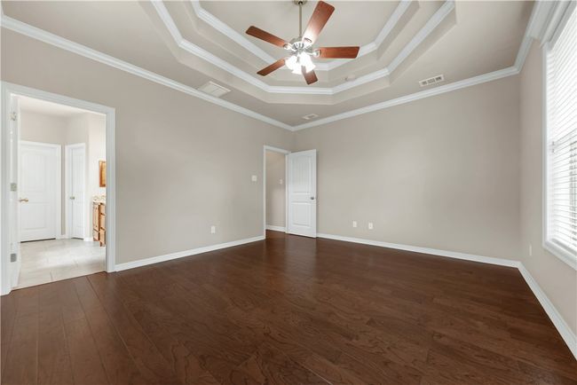 Unfurnished room featuring a raised ceiling, ceiling fan, dark wood-style floors, ornamental molding, and baseboards | Image 20