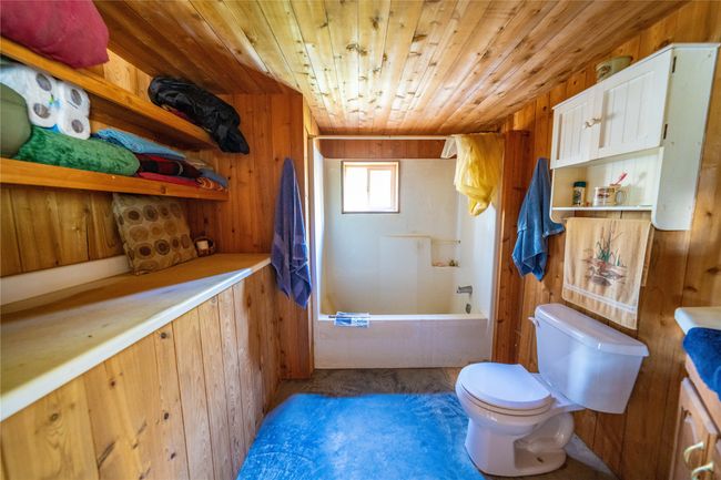 Bathroom featuring toilet, washtub / shower combination, wooden walls, and wooden ceiling | Image 26