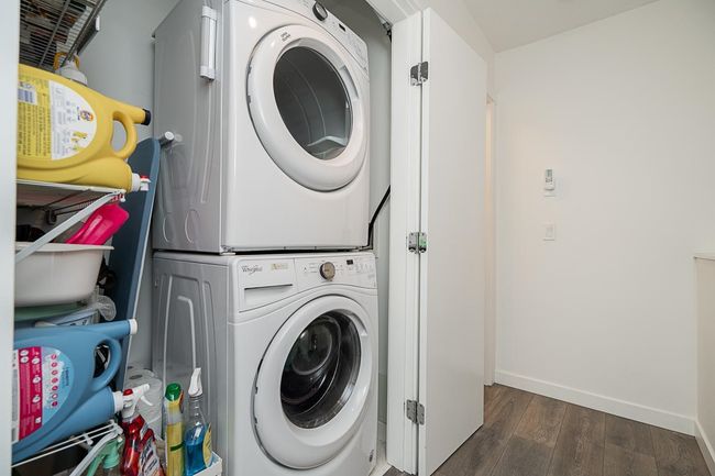 Clothes washing area with stacked washer and dryer, dark wood finished floors, laundry area, and baseboards | Image 26