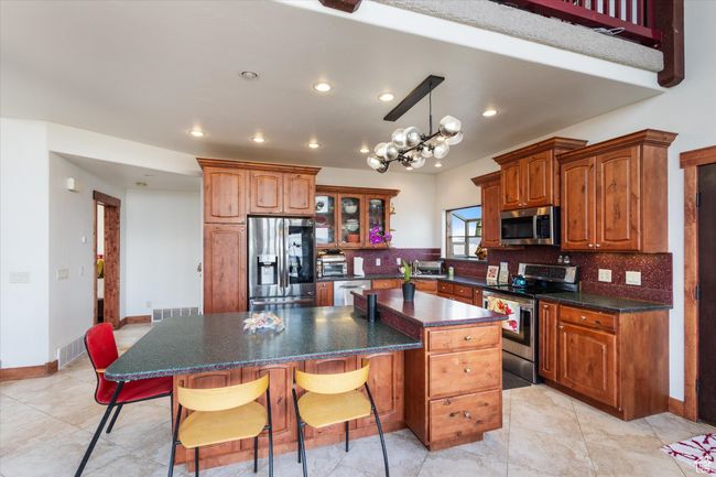 Kitchen with a kitchen bar, backsplash, appliances with stainless steel finishes, and a kitchen island | Image 8
