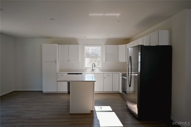 Kitchen with appliances with stainless steel finishes, dark hardwood / wood-style floors, white cabinetry, sink, and a center island | Image 5