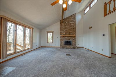 Living room with large windows that let in natural light and vaulted ceilings with wood burning fireplace | Image 3