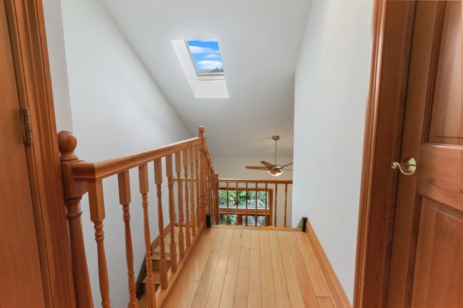 Hall featuring a skylight, an upstairs landing, vaulted ceiling, and light wood finished floors | Image 30