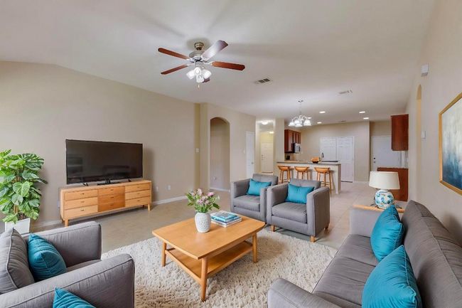 Living area with ceiling fan with arched walkway, hard tile flooring and view to back yard. Virtually staged picture. | Image 8