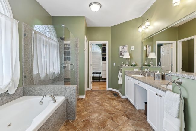 Primary bath features an oversized jetted tub, large glassed shower, double sink vanity and separate water closet. | Image 23