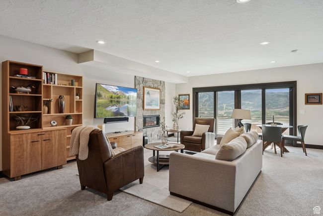 Living room featuring light colored carpet, recessed lighting, a textured ceiling, and a stone fireplace | Image 43
