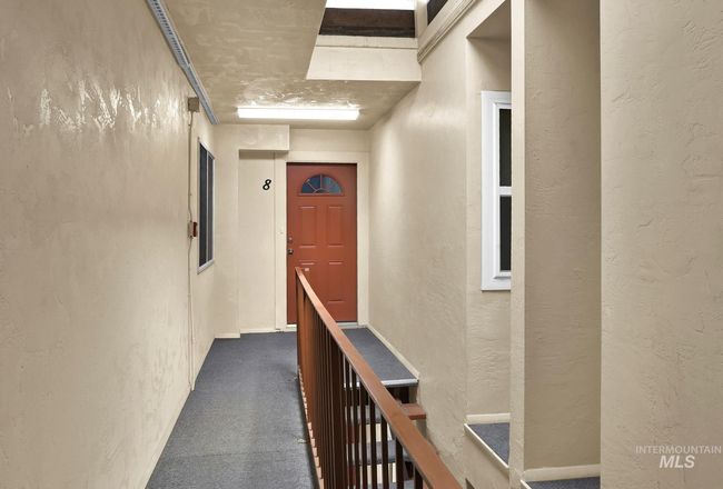 Hallway featuring a textured wall, dark carpet, and an upstairs landing | Image 5