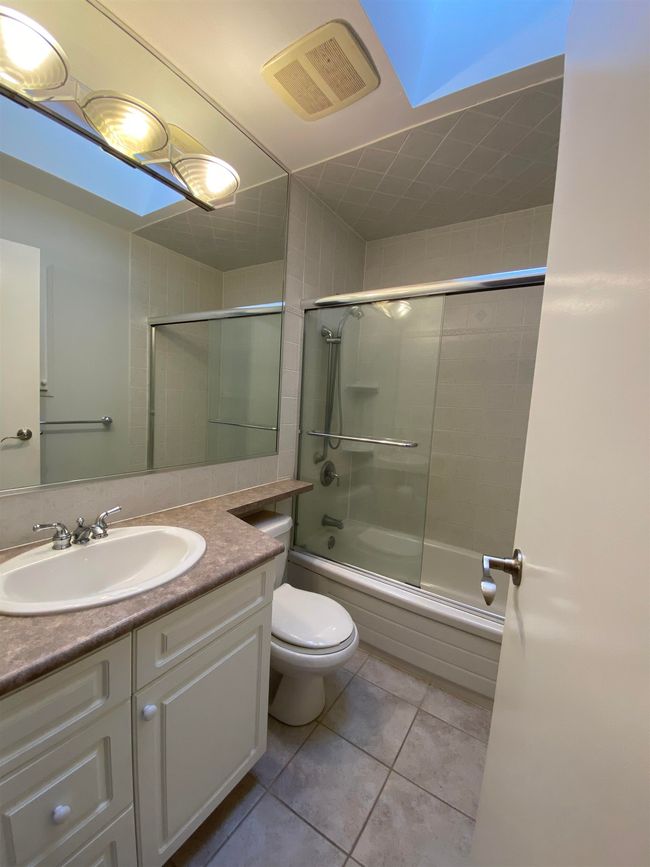 Full bath featuring toilet, vanity, visible vents, tile patterned floors, and enclosed tub / shower combo | Image 7