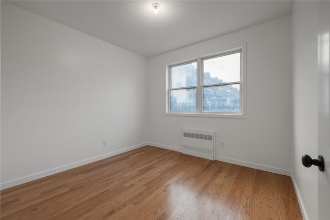Unfurnished room with radiator heating unit, baseboards, and light wood finished floors | Image 31