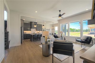 Living room featuring hardwood / wood-style flooring and ceiling fan with notable chandelier | Image 2