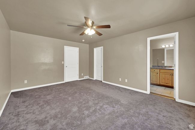 Unfurnished bedroom with carpet flooring, connected bathroom, and a ceiling fan | Image 12