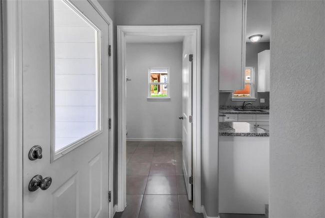 The back hall behind the kitchen provides access to the laundry room, the back door and the primary bedroom suite. | Image 17