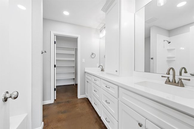 Full bath featuring double vanity, a sink, a shower, and finished concrete floors | Image 11